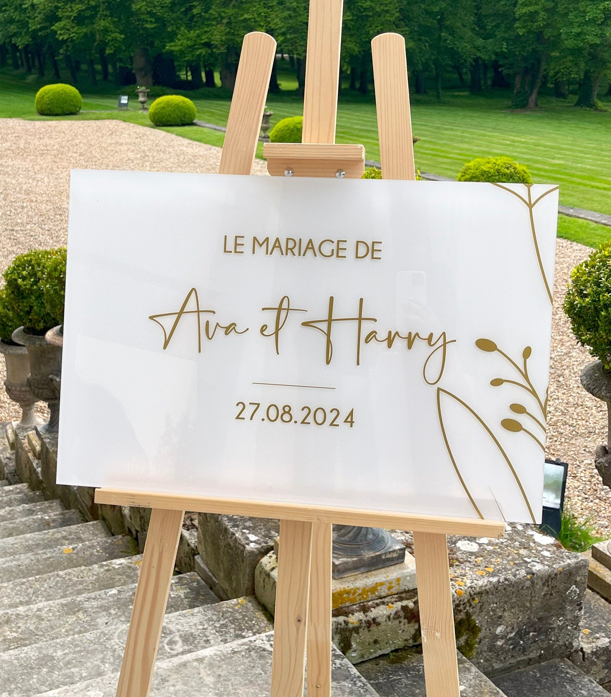 Panneau de bienvenue de mariage en plexiglass givré avec texte et fleur dorés, design minimaliste et élégant