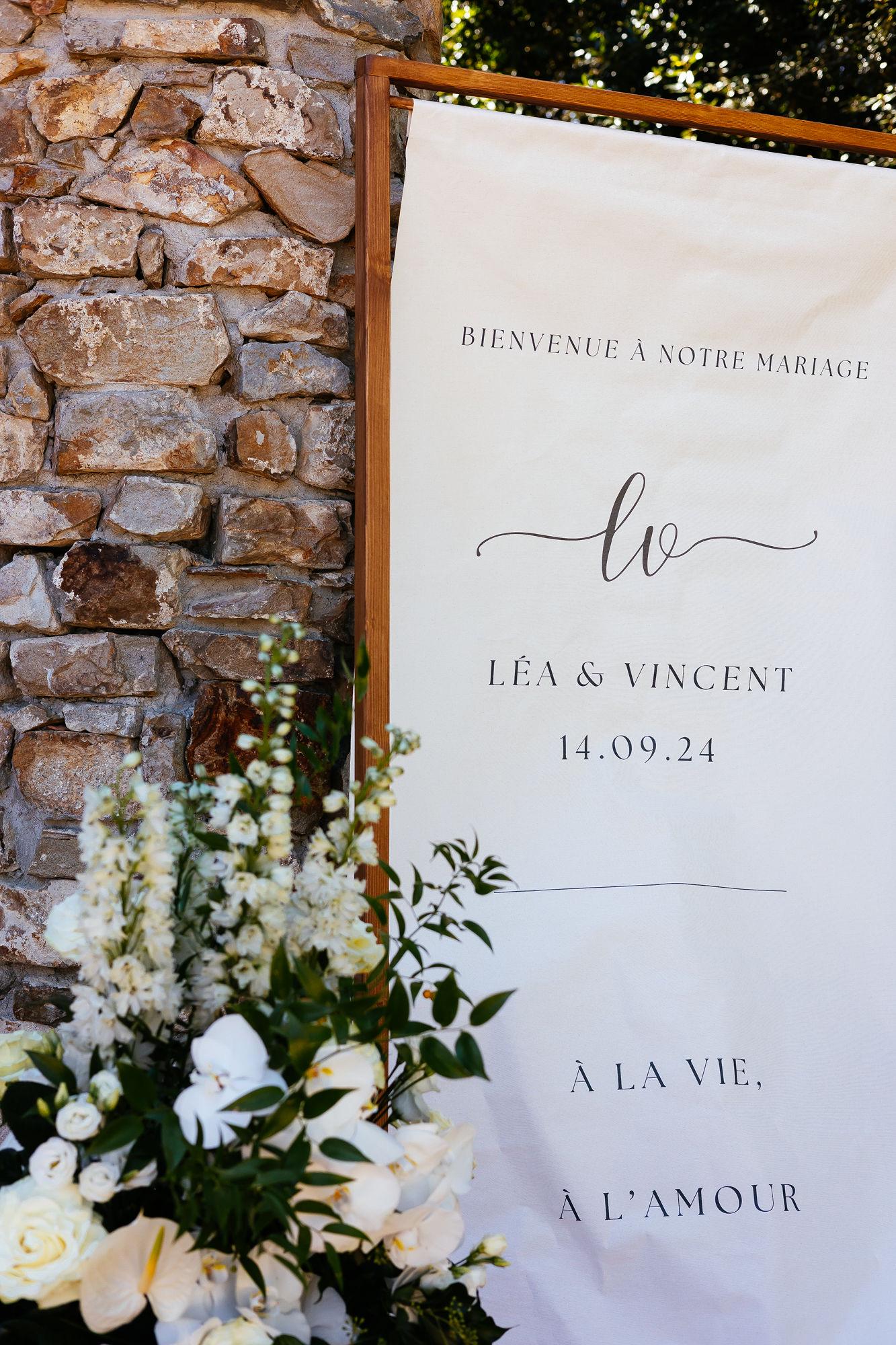 Panneau de bienvenue en tissu style lin naturel, typographie fine avec initiales, pour une décoration de mariage moderne et épurée.