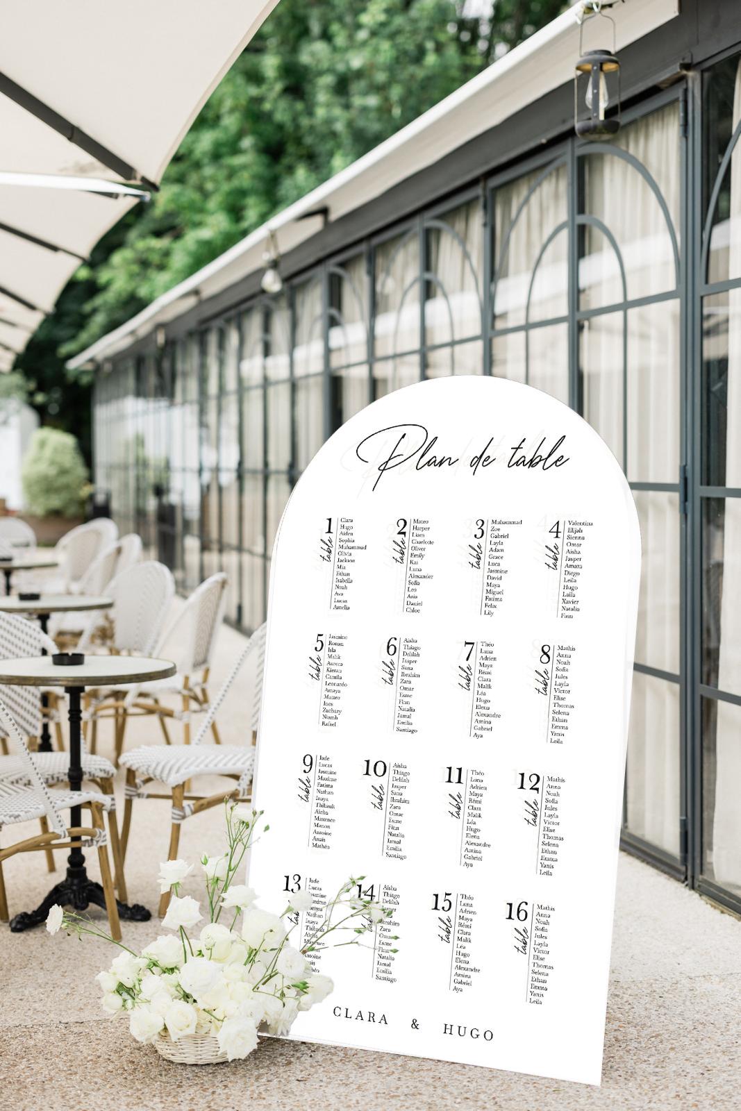 Plan de table mariage en arche 180 cm, réalisé en forex blanc, personnalisé avec les prénoms des mariés et la disposition des invités.