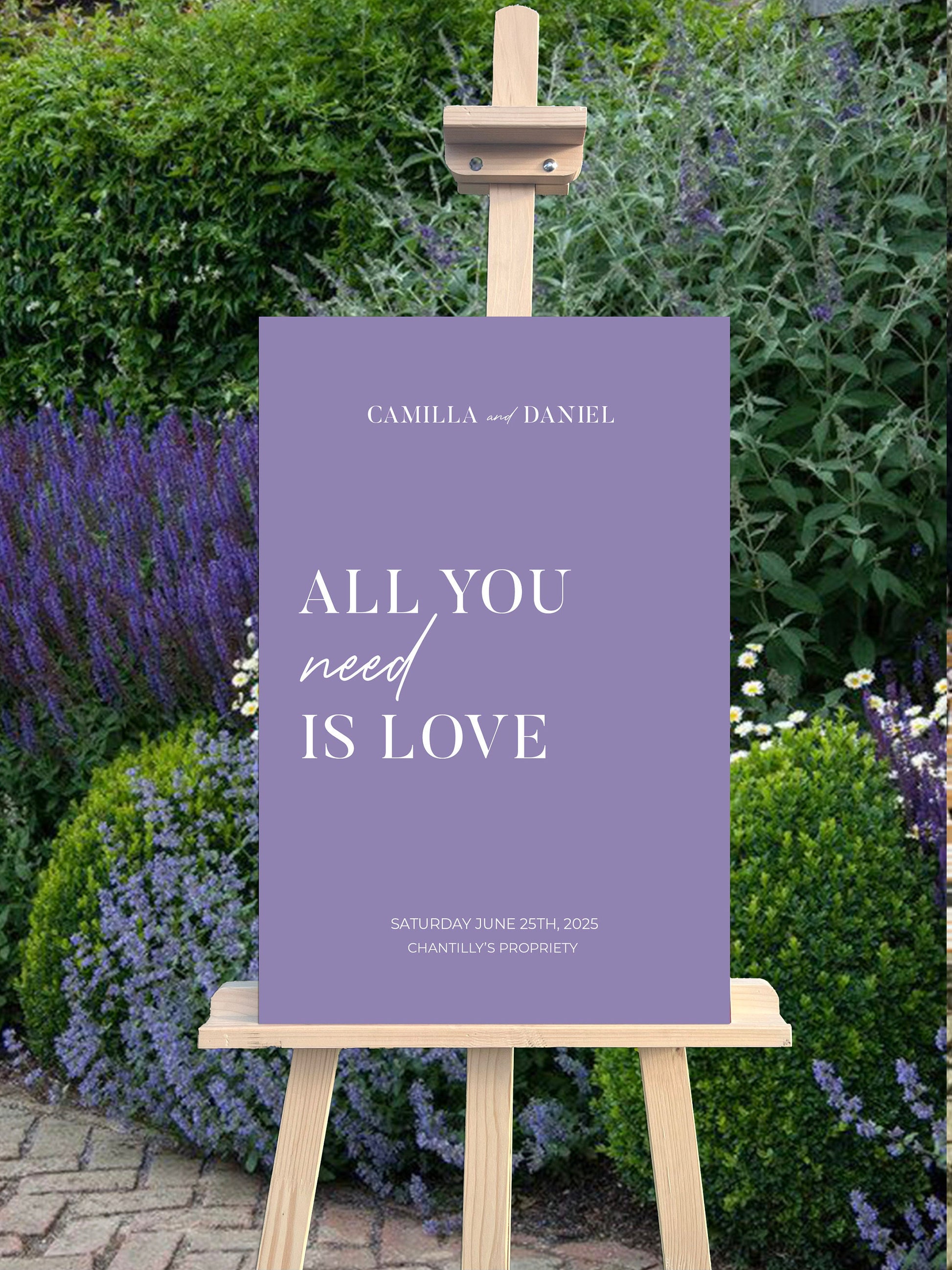 Panneau de bienvenue mariage en forex lila, personnalisé avec prénoms, lieu et date, décoré de la citation "All you need is love" pour une ambiance romantique et moderne.