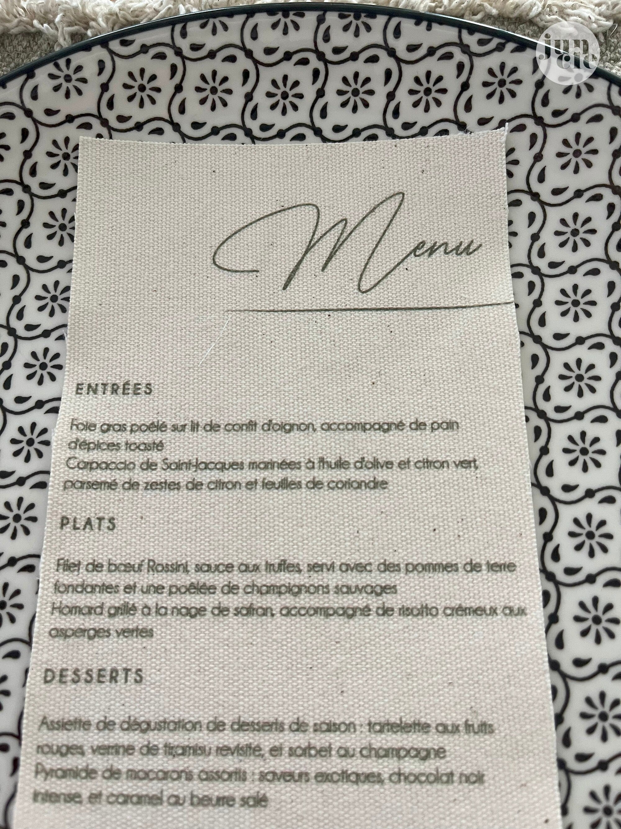 Gros plan sur le menu de mariage en lin, texture naturelle du tissu et impression raffinée du texte personnalisé.