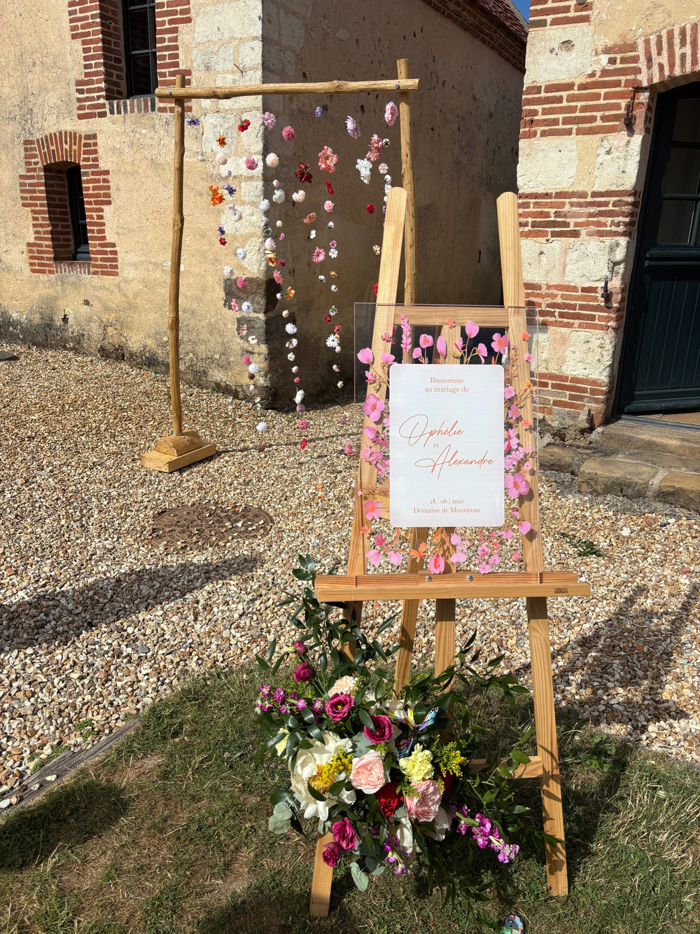 Panneau de bienvenue en plexiglass décoré de fleurs oranges et roses, idéal pour une décoration de mariage élégante et colorée.